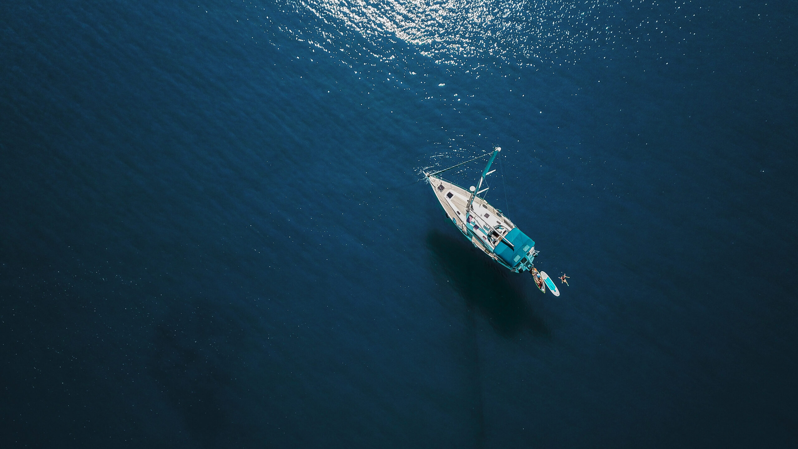 Aerial shot of beautiful blue lagoon at hot summer day with sailing boat. Top view.