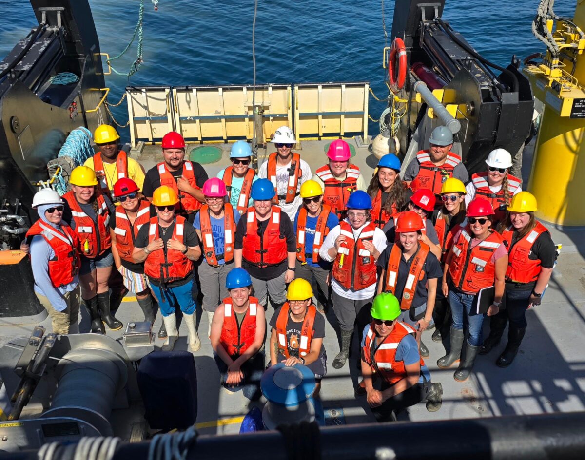 Attendees stand on the R/V Lake Guardian wearing life jackets and helmets