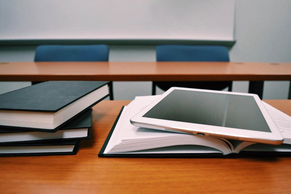 A stack of books and computer tablet in a classroom.