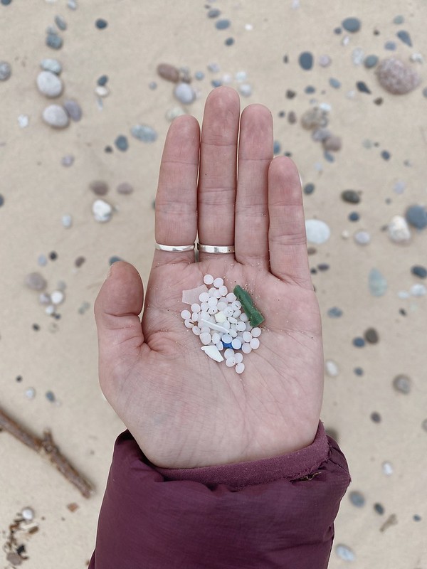 Plastic nurdles in a hand over a beach