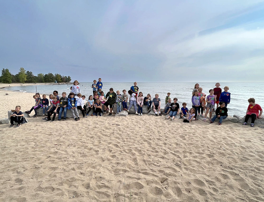 Group of students pose on the beach at Tawas Point State Park in Michigan along the shores of Lake Huron