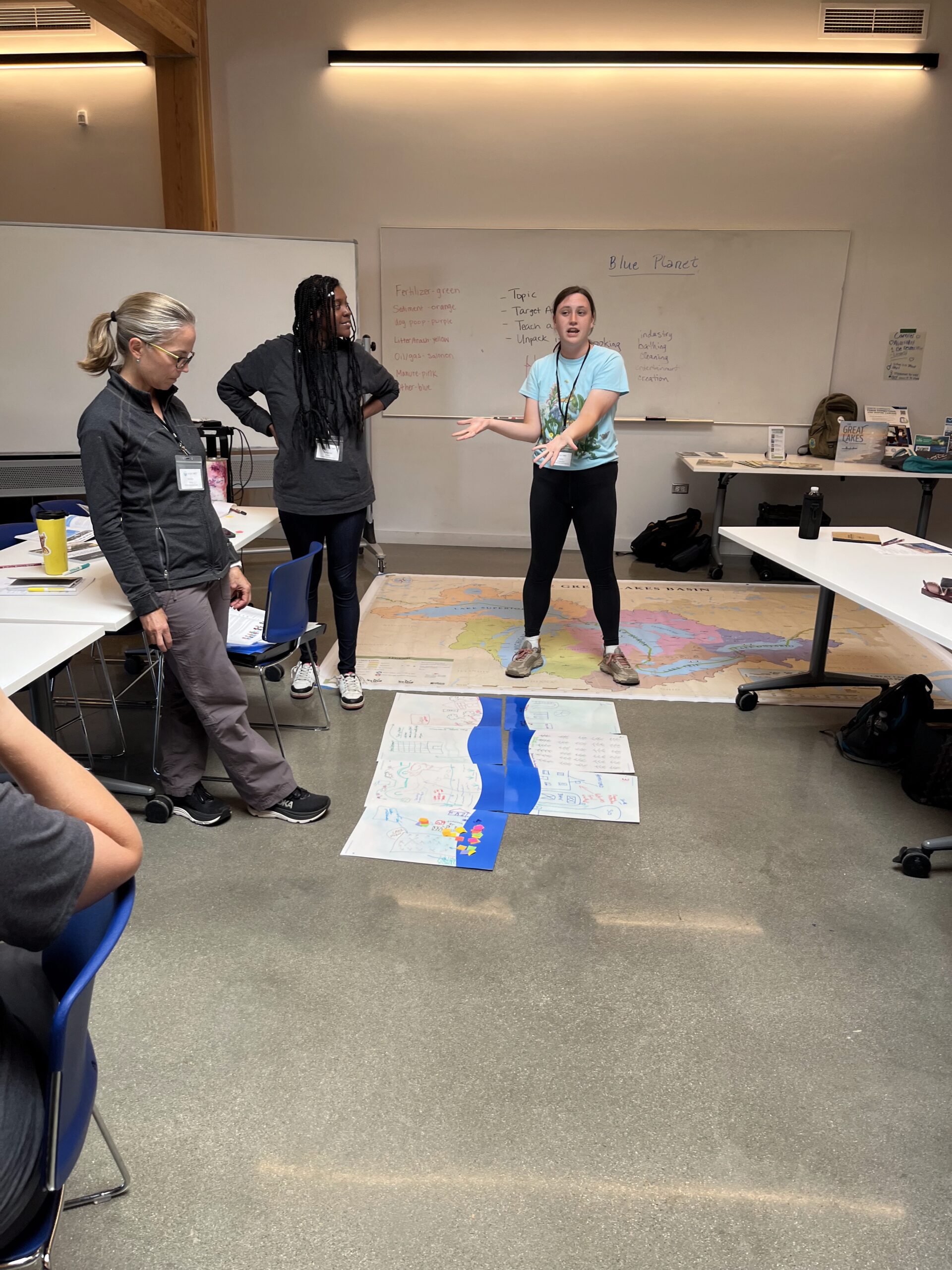 Educators learning around the Great Lakes basin map and paper-flowing river.