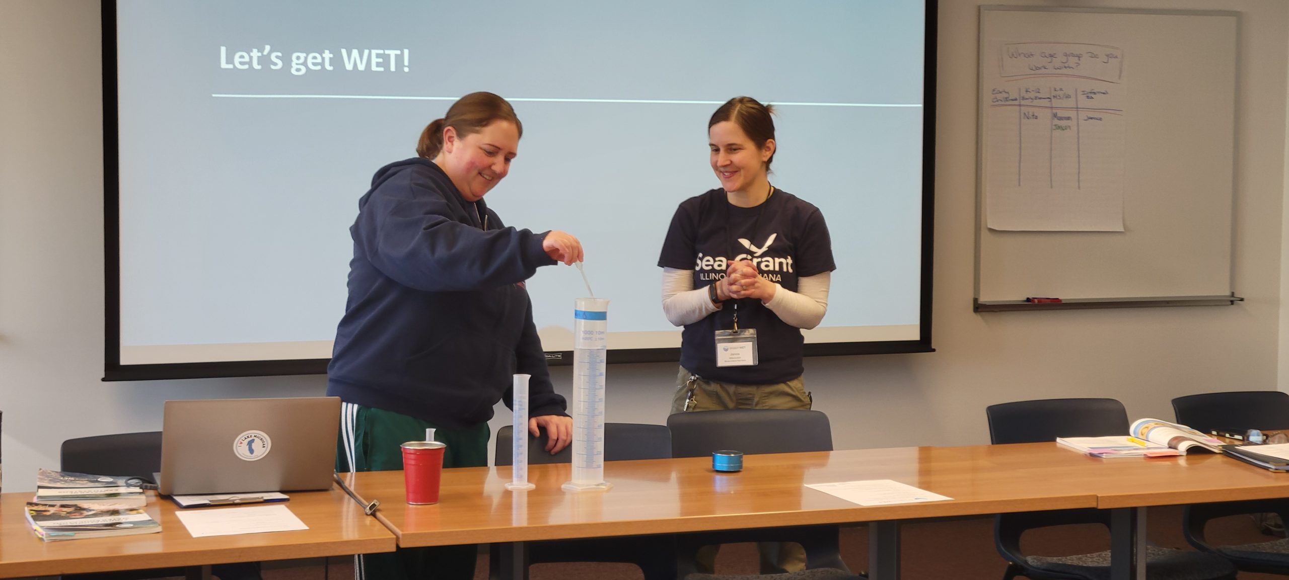 Educators mix water in a graduated cylinders.